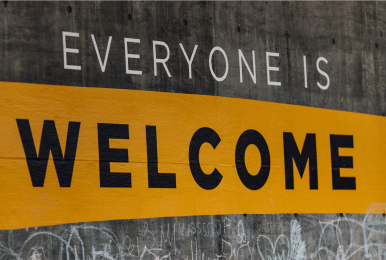 Text on grey background, white text reads "Everyone is" and on a yellow background in black bold text reads "Welcome".
