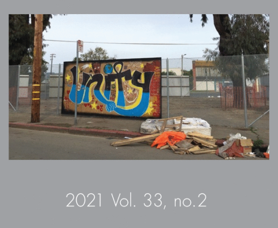 street with graffiti billboard on a chainlink fence with trash on the right side and a wooden post on the left